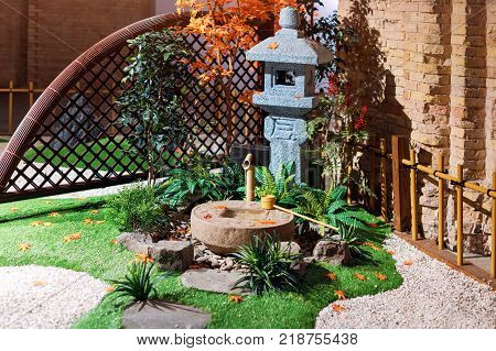 Japanese stone lantern in the garden with cho-zu fountain and maple. Traditional asian fountain in the park