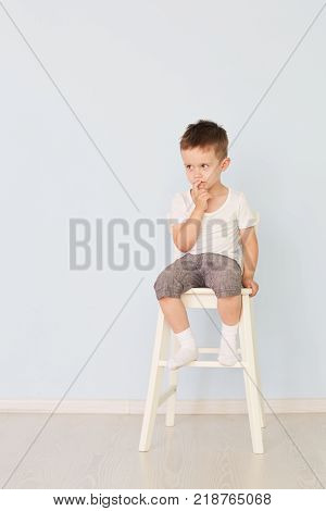European teenage boy in a white shirt and blue shorts sitting on a chair with the tablet computer. Looking at the camera. Studio shot, isolated on white background.