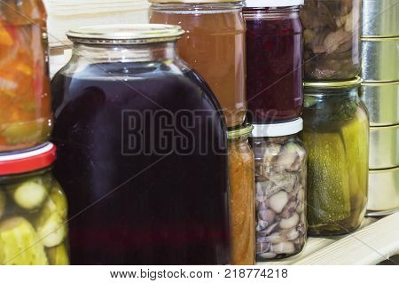 Storage shelves in pantry with homemade canned preserved fruits and vegetables.