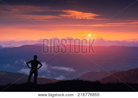 Silhouette of hiker on a hill against colorful majestic sunset in a Carrpathian mountains.