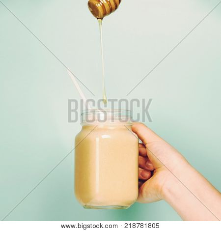 Woman (teenage girl) hand holding smoothie shake against bright wall. Drinking  healthy smoothie concept