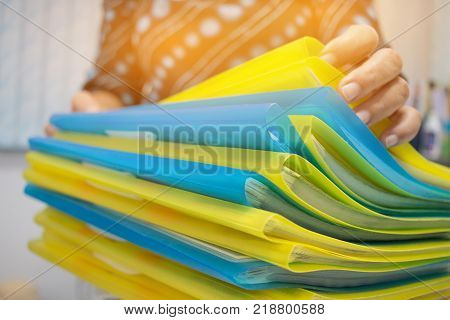 Asian Businesswoman hands working in many documents Stacks of folders in office for Annual Report files Piles of color folder close annual budget business busy concept.