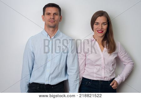 Close up portrait of middle aged couple - cute positive woman in pink shirt and charming young man in blue shirt look at the camera on white background