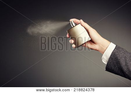 Man applying Perfume. Man's Perfume in the Hand on Black Background