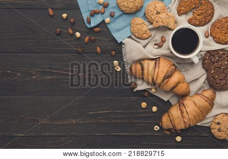 French croissants and coffee background. Tasty french breakfast with variety of homemade cookies, nuts and buns. Mockup for sweet pasrty recipe, top view, copy space