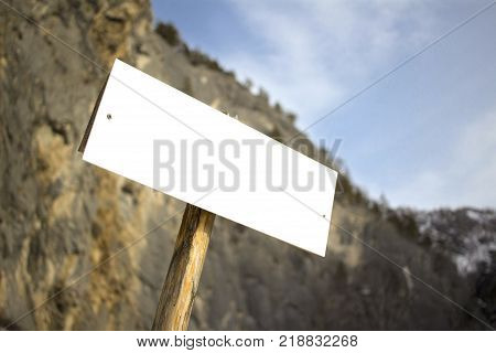 Adventure blank board white sign on bokeh mountains view on sunny day rock climbing alpinism tourists
