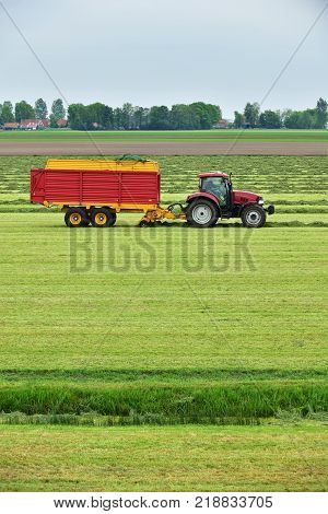 Tractor Pulling A Forage Wagon And Collecting Cutted Hay Silage Into A Self-loading Silage Wagon In 