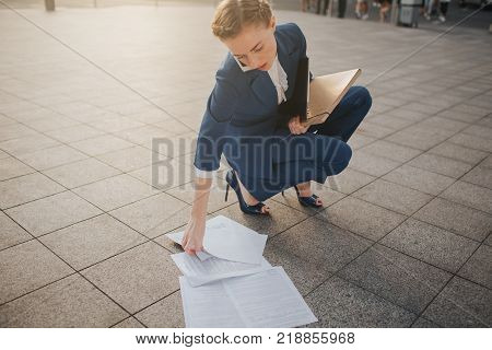 Overworked business woman having a lot of paperwork. Business woman surrounded by lots of papers. Business woman standing in the heap of papers
