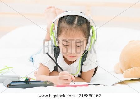 Little girl listen to music from headphone while drawing picture,relaxing and education concept.