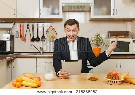 Perturbed Young Business Man In Suit, Shirt, Having Breakfast, Sitting At Table With Tablet, Spreadi