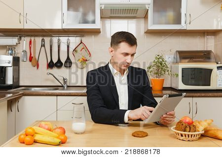 Perturbed Young Business Man In Suit, Shirt, Having Breakfast, Sitting At Table With Tablet, Spreadi