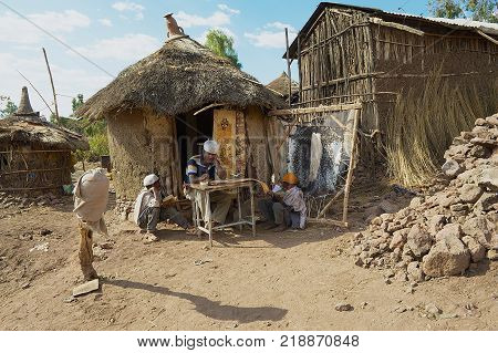 LALIBELA, ETHIOPIA - JANUARY 27, 2010: Unidentified people paint and read at the house entrance in Lalibela, Ethiopia. Ethiopia has one of the highest levels of illiteracy in the world.