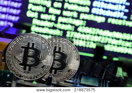 The digital process of cryptocurrency mining by using the GPUs. Bitcoins and video card on a working display and mining screen