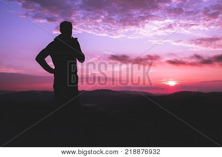 Silhouette of a man with a Smoking pipe on a background of dramatic purple red sky and sunset