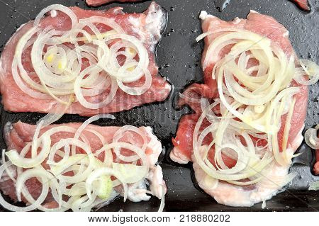 Raw pork chops on a black baking tray. Process of cooking step by step. Top view, flat lay.