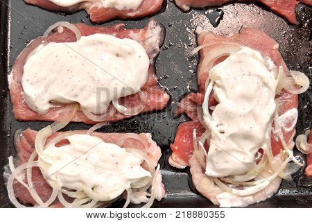 Raw pork chops on a black baking tray. Process of cooking step by step. Top view, flat lay.