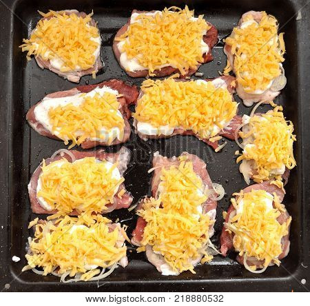 Raw pork chops on a black baking tray. Process of cooking step by step. Top view, flat lay.