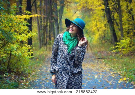 Pretty romantic girl in autumn clothes walks in a park. The mood of autumn, leaf fall. Autumn fashion.
