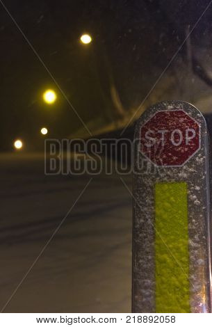 Red stop sign in winter snowy conditions. Nigt city blizzzard
