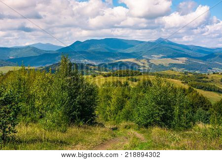 beautiful countryside of Crapathians in early autumn. forested hills and mountain ridge with high peak in the distance. lovely sunny weather with cloudy sky
