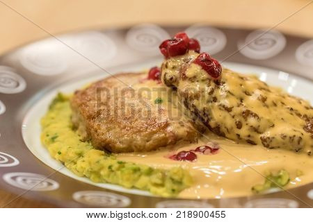 Meat patties or frikadeller in chese and mushroom sauce decorated with berries