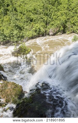 Croatian Village Of Rastoke By A River Canyon With Wooden Houses In A Green Lanscape With Trees And