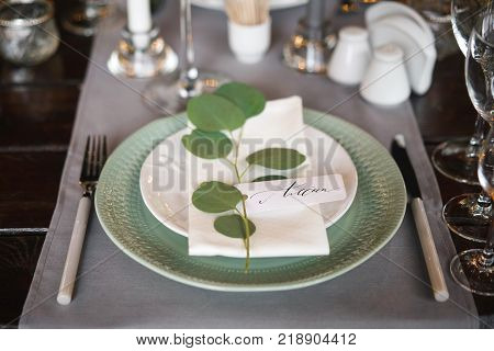 personal seating chart on a dinner party plate. The name written in ink and a pen calligraphy on white designer paper.
