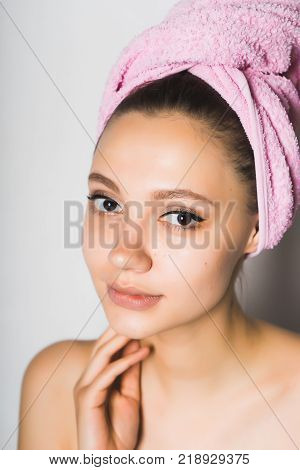 girl with a pink towel on her head on a gray background