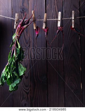 Fresh betroots hanging on string.Wooden background.Concept hanging herbs.free space
