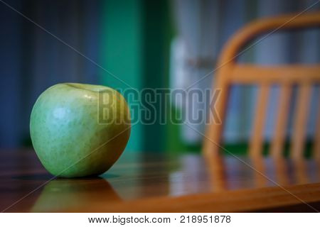 Fresh apple on wooden table with wooden chair in background