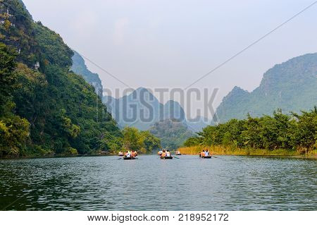 International tourists traveling on local vietnamese small boat along the Ngo Dong river of the Tam Coc, Ninh Binh, Vietnam.