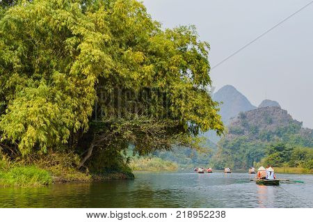 International tourists traveling on local vietnamese small boat along the Ngo Dong river of the Tam Coc, Ninh Binh, Vietnam.