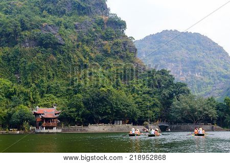 International tourists traveling on local vietnamese small boat along the Ngo Dong river of the Tam Coc, Ninh Binh, Vietnam.