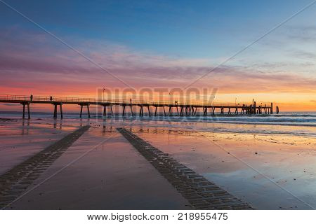 South Australia's Glenelg beach at sunset with tyre tracks in the foreground