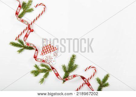 Christmas holiday composition. Festive creative red pattern, xmas handmade decor holiday with ribbon, candy canes, gift, christmas tree and decorations on white background. Flat lay, top view