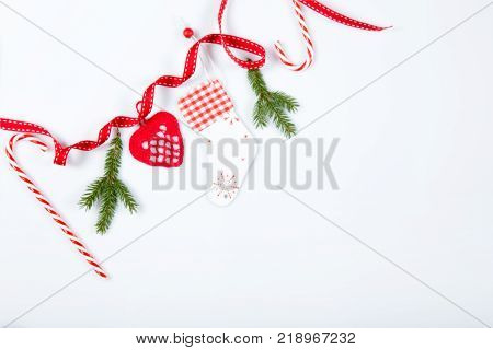 Christmas holiday composition. Festive creative red pattern, xmas handmade decor holiday with ribbon, candy canes, gift, christmas tree and decorations on white background. Flat lay, top view