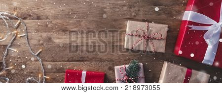 Christmas and new year background with gift boxes and string light decorations on wood banner background top view with coyp space