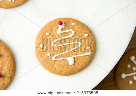Round homemade gingerbread cookie decorated with icing in Christmas tree shape on top