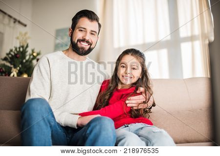 happy father and daughter hugging and looking at camera