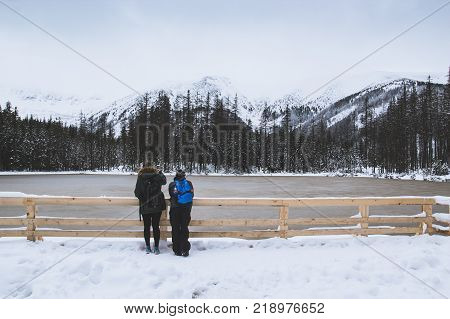 A guy and a girl look at the frozen lake