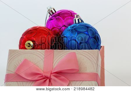 Christmas ornament with a redpurple and blue in a gift box on white background
