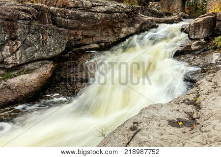 Powerful mountain river close up. Crystal water flows through mossy boulders and rocks. Dark vintage toning filter. Buky Canyon on the Hirs`kyi Tikych river in Ukraine.