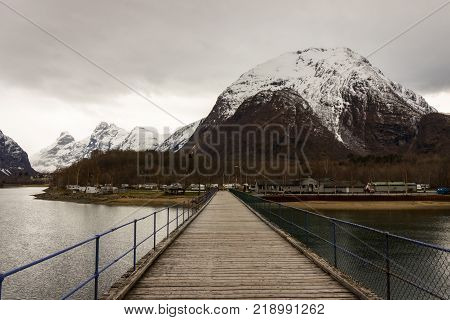Rauma, Romsdalen in Norway - April, 19, 2017: A wooden bridge over the Rauma river leads to Andalsnes Camping, located close to Trollveggen and Trollstigen, both famous tourist attractions.