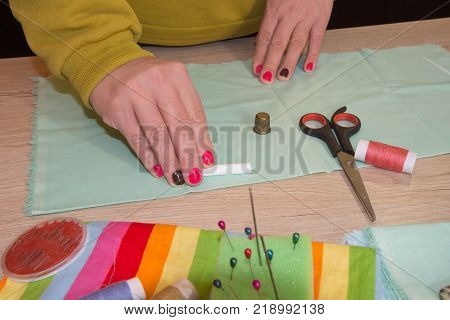 woman's hands drawing a pattern on bright material at her workplace in a tailor shop. Clothes designer at work in her office