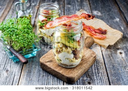 Brotzeit im Glas â traditional Bavarian snack with ham, eggs and black bread in a glass as closeup on a wooden board 