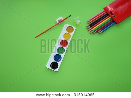 Brush, Paint, Eraser, Pencils On A Green Background. Watercolor And Colored Objects For School And C