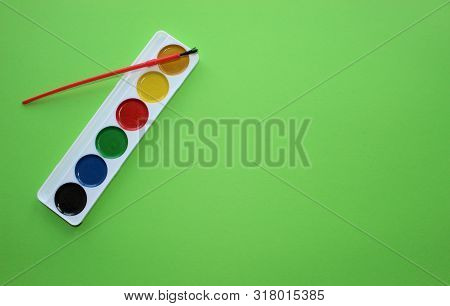 Brush, Paint, Eraser, Pencils On A Green Background. Watercolor And Colored Objects For School And C
