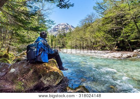 Man Sit Alone On Rock Near Azusa River At Kamikochi In Northern Japan Alps.