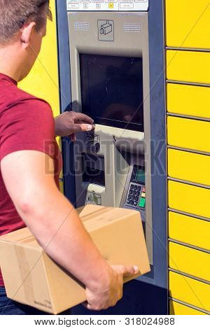 Man Client Using Automated Self-service Post Terminal Machine Or Locker To Depisit A Parcel For Stor