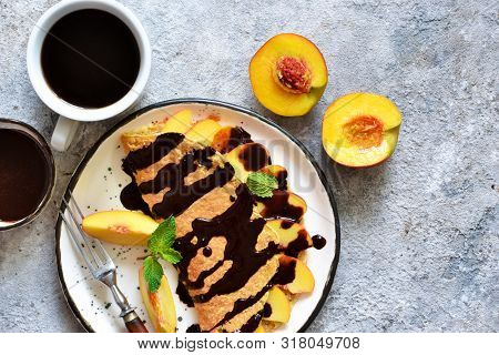 Classic Breakfast - Crepes With Caramel Peaches And Chocolate Sauce. Breakfast And A Cup Of Coffee.